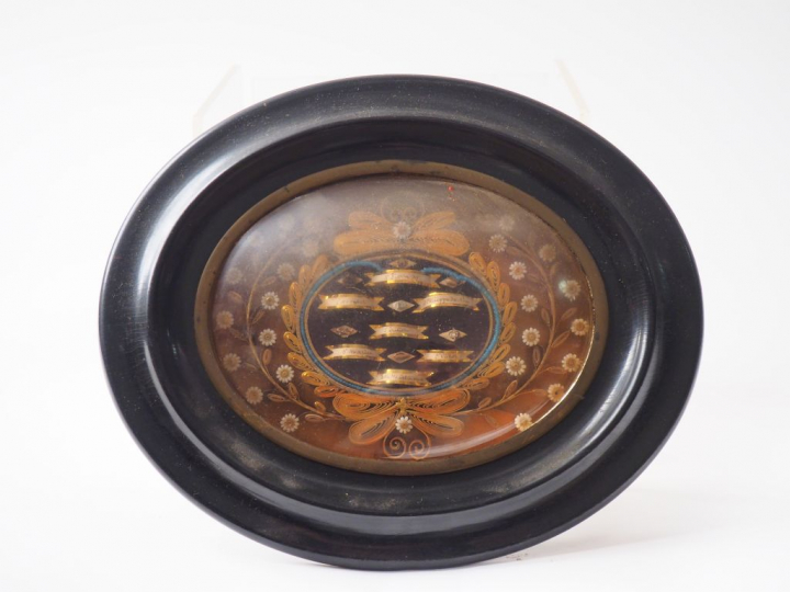 Reliquaire ovale XIXème en paperolle, cadre en bois noirci. Dim. 18,5 