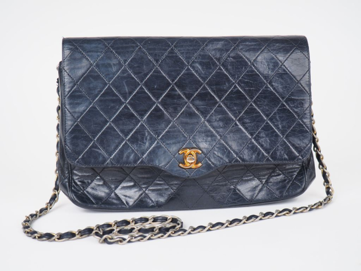 Sac bandoulière en cuir matelassé bleu.  Fermeture à rabat agrémentée 