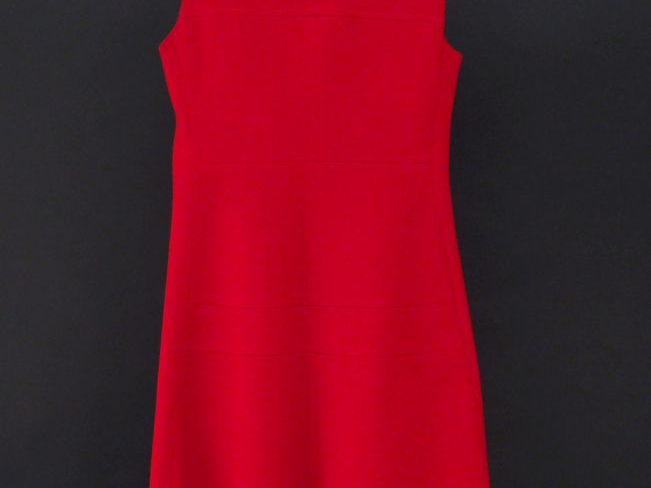 Robe rouge sans manche. Quatre fauses poches à rabat.  Fermeture à zip