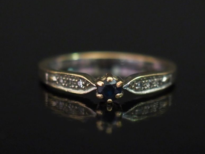 Bague en or blanc 750, sertie en son centre d'une pierre bleue épaulée