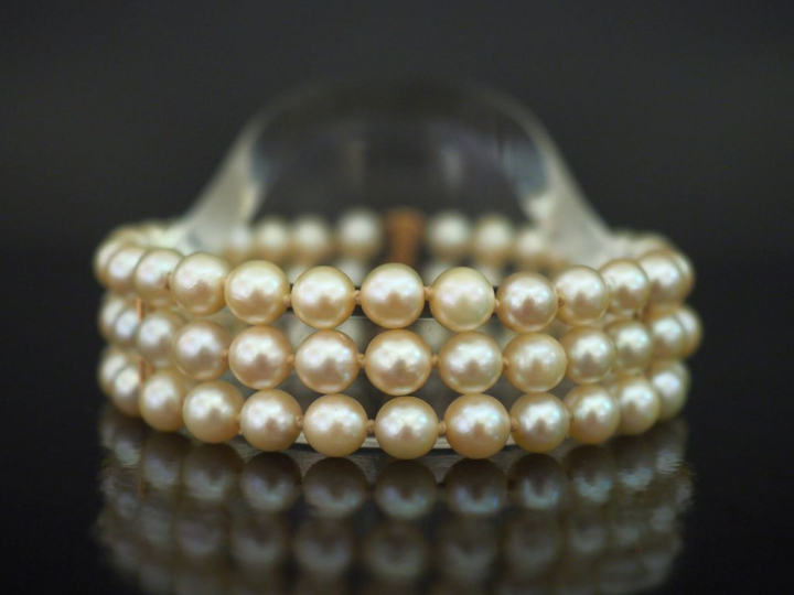 Bracelet triple rangs de perles blanches.  Fermoir en or jaune 750. Lo