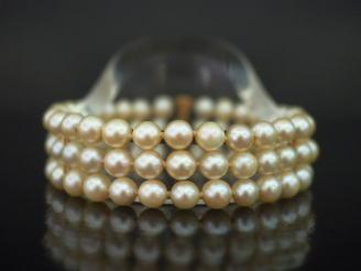 Vente aux enchères Bracelet triple rangs de perles blanches.  Fermoir en or jaune 750. Lo