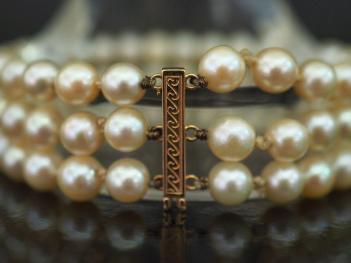 Bracelet triple rangs de perles blanches.  Fermoir en or jaune 750. Lo
