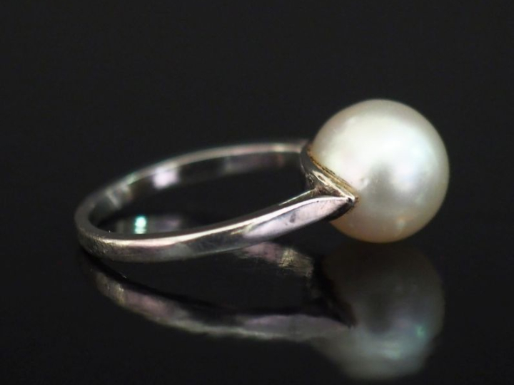 Bague en or blanc 750, sertie en son centre d'une perle blanche.  TDD.