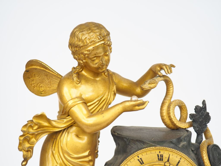 Pendule Restauration en bronze patiné et doré, à décor d'amour au serp