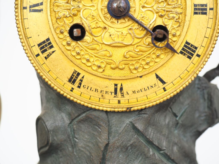 Pendule Restauration en bronze patiné et doré, à décor d'amour au serp