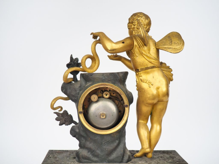 Pendule Restauration en bronze patiné et doré, à décor d'amour au serp