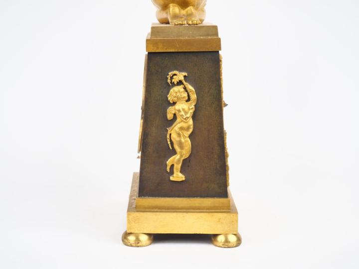 Pendule borne Empire en bronze à patine verte et dorée représentant un