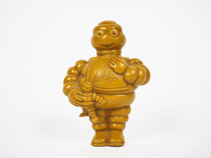 MICHELIN. Bibendum, sujet en résine jaune. H. 9,5 cm.