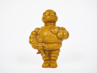 Vente aux enchères MICHELIN. Bibendum, sujet en résine jaune. H. 9,5 cm.