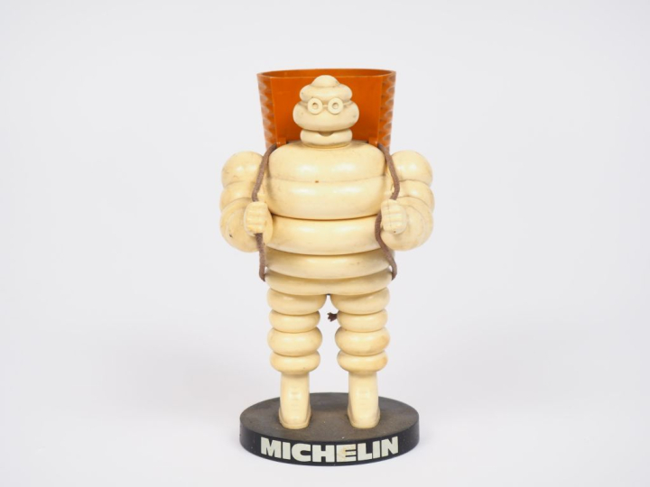 MICHELIN.  Porte crayon Bibendum vendangeur en plastique et métal. H. 