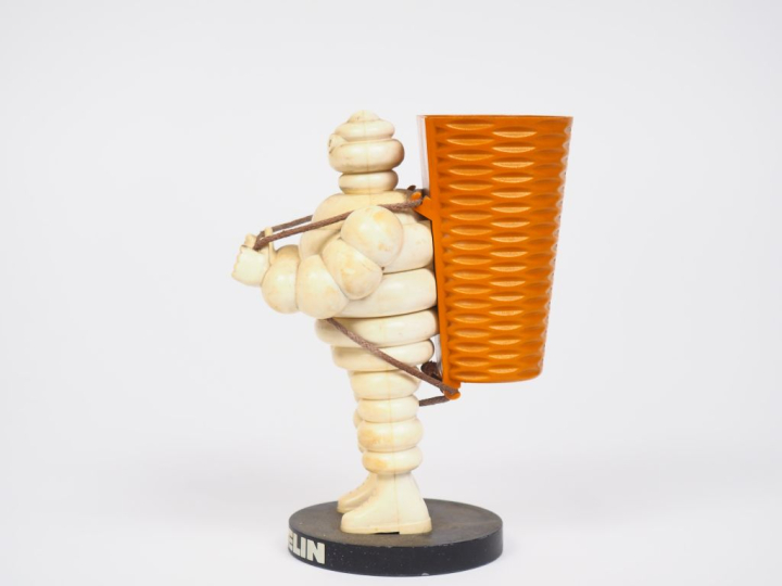 MICHELIN.  Porte crayon Bibendum vendangeur en plastique et métal. H. 