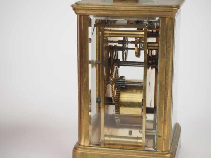 Dans son écrin en cuir rouge, pendulette de voyage en bronze et crista