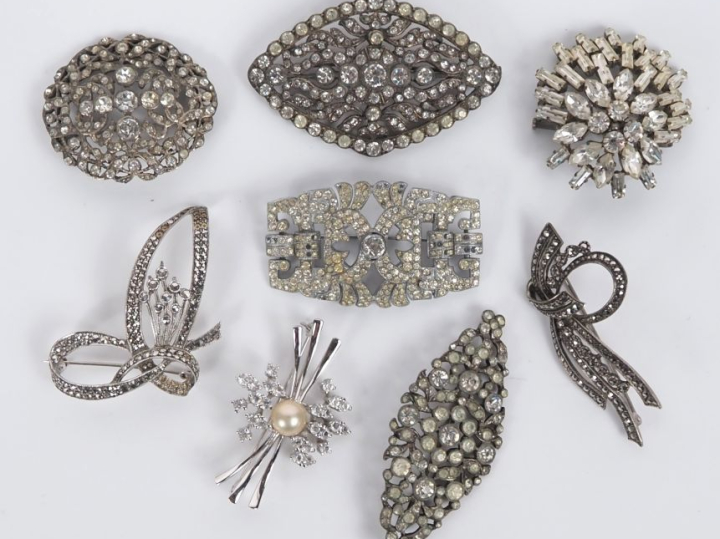 8 différentes broches en métal argenté et imitation de diamant. L. de 