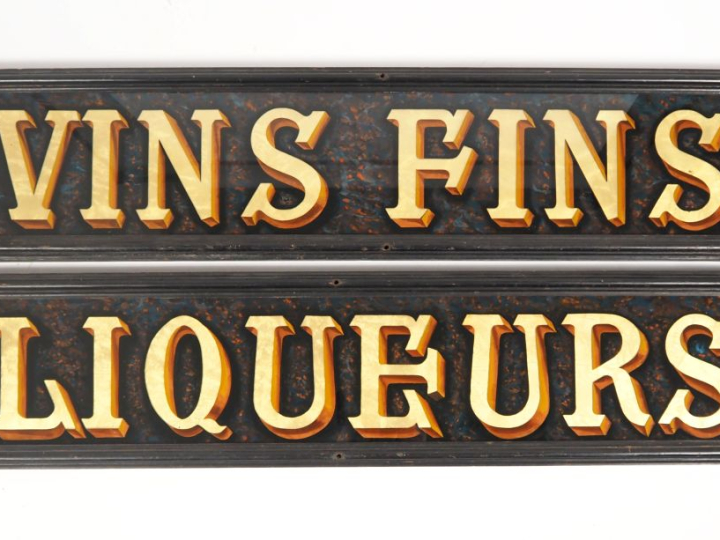 Deux enseignes polychromes et dorées, "vins fins" et "liqueurs", dans 