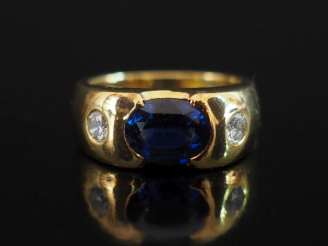 Vente aux enchères Bague bandeau en or jaune 750, sertie en son centre d'un saphir épaulé
