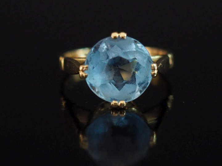 Bague en or jaune 750, sertie en son centre d'une pierre bleu ciel.  T