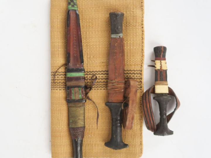 Trois poignards africains en bois et cuir.  Longueur : 16, 26 et 37 cm