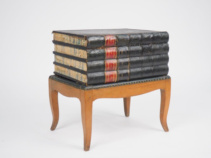 tabouret en trompe l'œil figurant une pile de livres, ouvrant à un aba