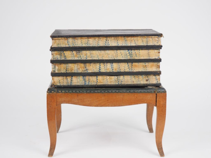 tabouret en trompe l'œil figurant une pile de livres, ouvrant à un aba