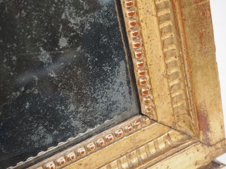 Miroir de style Louis XVI en bois sculpté et doré, fronton ajouré à dé