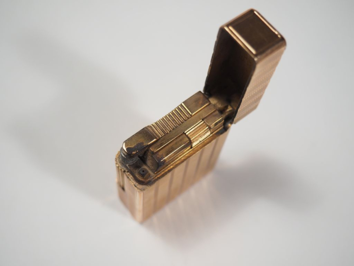 Briquet Dupont en métal doré, à décor de stries. Signé.  4,8 x 3,6 cm 