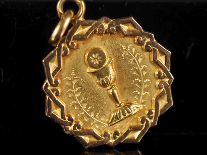 Médaille religieuse en or jaune 750, à décor de calice.  Joli pourtour