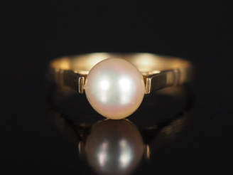 Vente aux enchères Bague en or jaune 750, sertie en son centre d'une perle blanche.  TDD.
