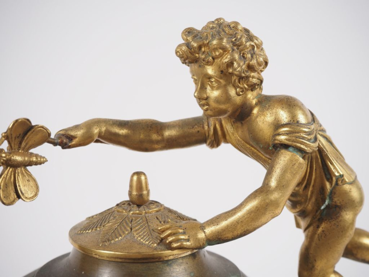 Pendule de style Empire en bronze, à double patine, figurant un amour 