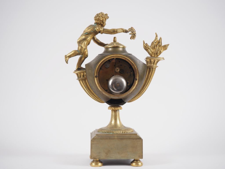 Pendule de style Empire en bronze, à double patine, figurant un amour 