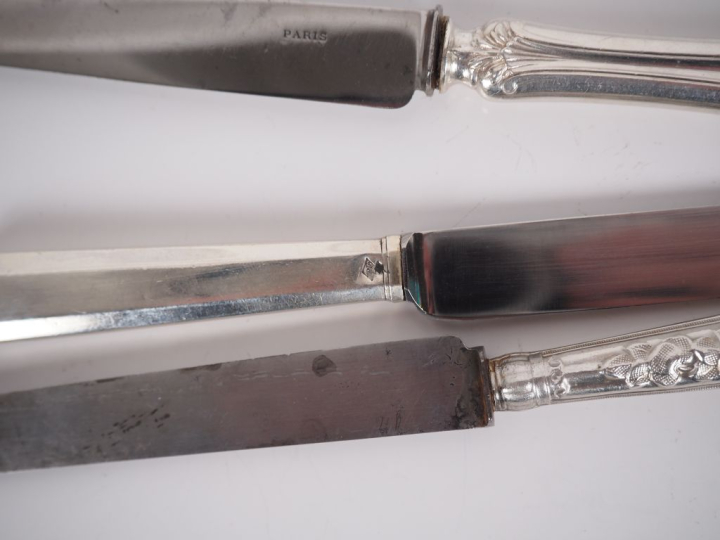Différentes séries de couteaux en métal argenté.