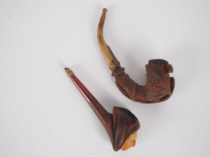 Deux différentes pipes en corne et bois sculpté, l'un figurant un visa