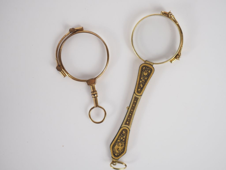Deux binocles dépliantes en métal doré ou laiton, l'une à décor de rin