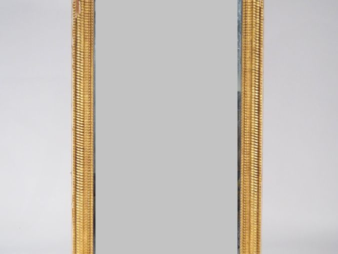 Glace de cheminée Napoléon III en bois et stuc doré, cadre guilloché. 