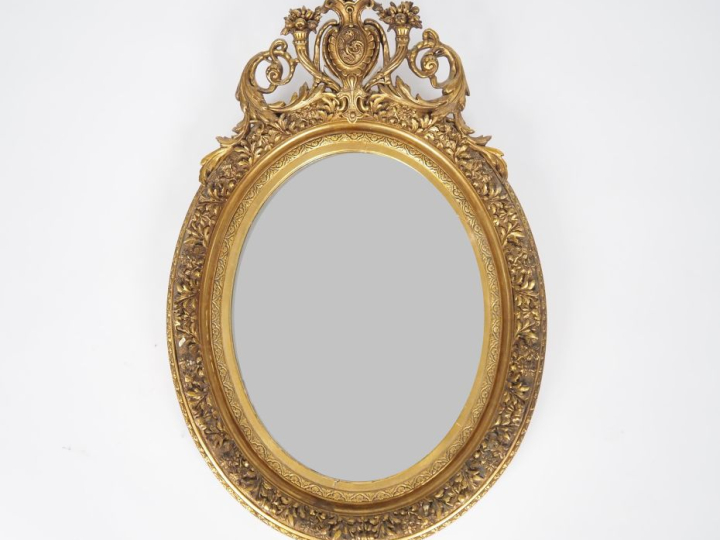 Glace médaillon de style Louis XVI en bois et stuc doré, à décor de fl