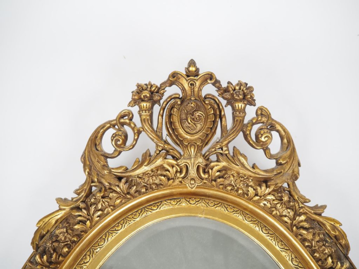 Glace médaillon de style Louis XVI en bois et stuc doré, à décor de fl