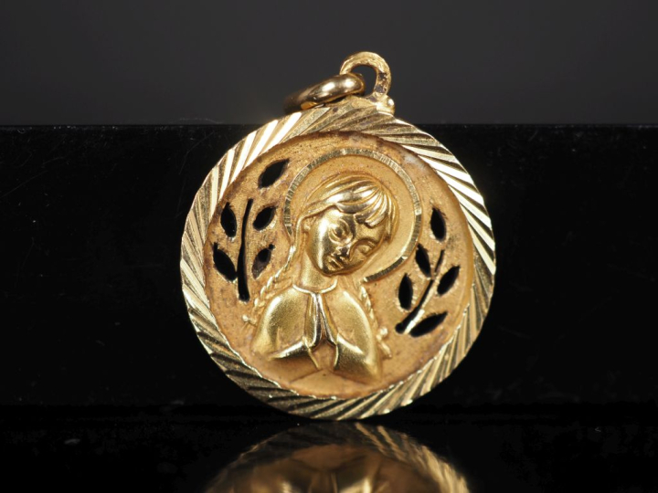 Médaille religieuse en or jaune 750, figurant une petite sainte les ma