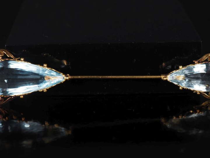 Broche en or jaune 750, sertie à ses extrémités d'une pierre bleu ciel