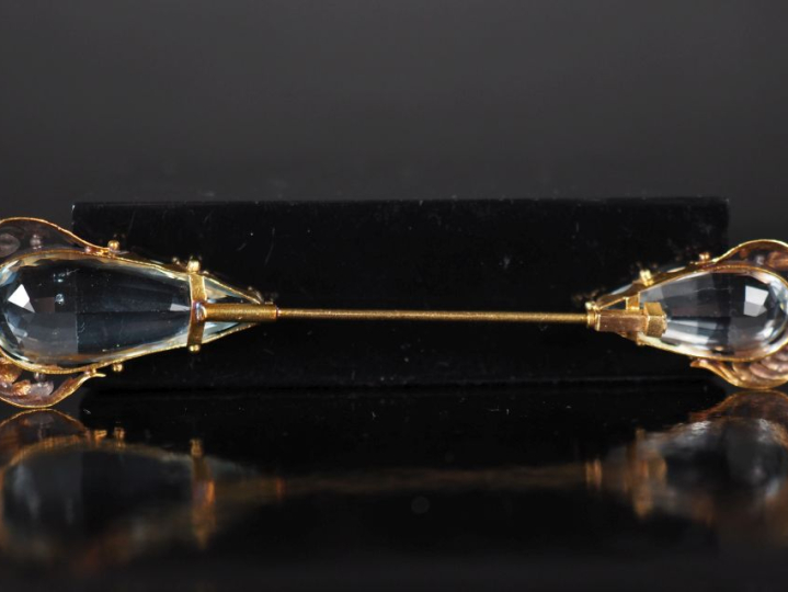Broche en or jaune 750, sertie à ses extrémités d'une pierre bleu ciel