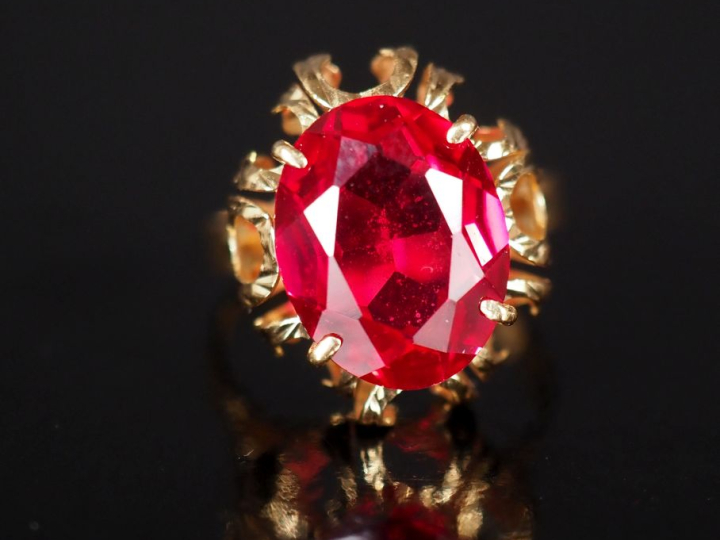 Bague en or jaune 750, sertie en son centre d'une pierre rouge.  Jolie