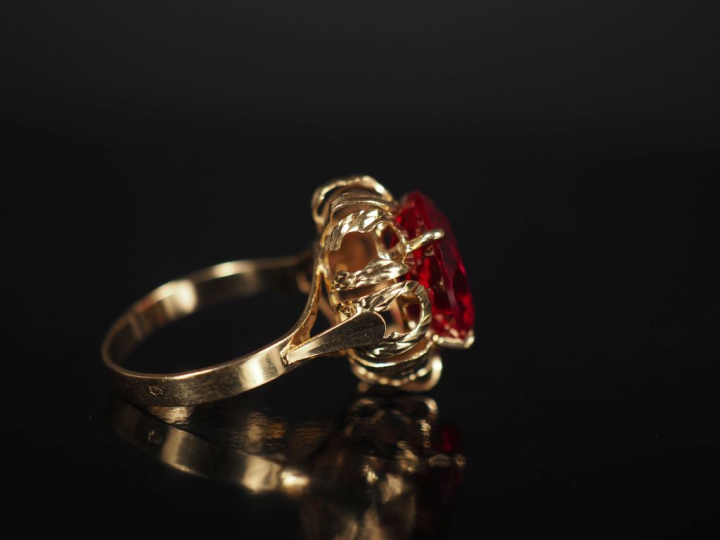 Bague en or jaune 750, sertie en son centre d'une pierre rouge.  Jolie