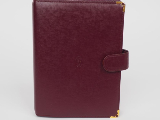 Vente aux enchères CARTIER, Paris Protège agenda et porte-cartes en cuir bordeaux.  Ferme