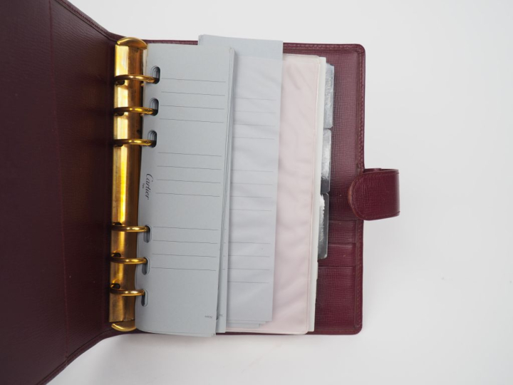 CARTIER, Paris Protège agenda et porte-cartes en cuir bordeaux.  Ferme