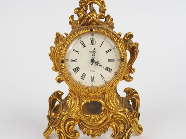 LANCEL, Paris Pendulette de style Louis XV en métal doré. Cadran rond 