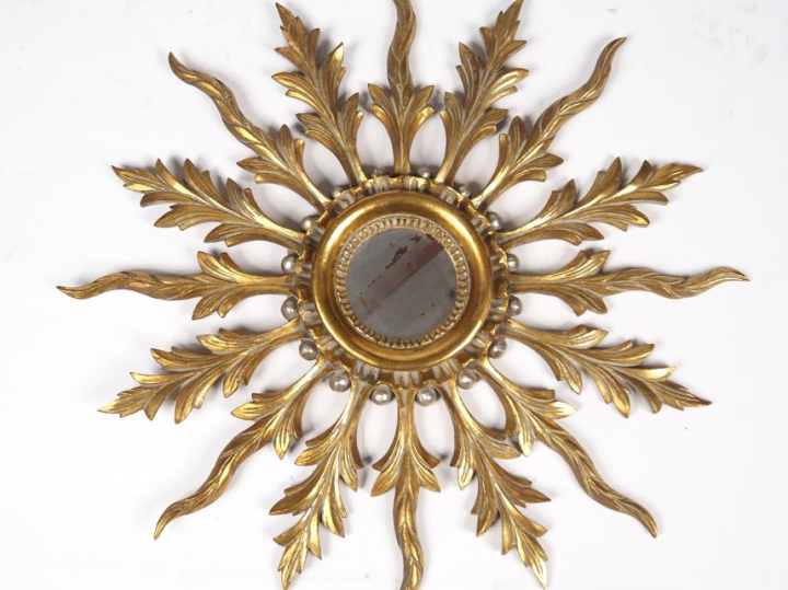 Miroir soleil en bois doré, à décor de palmes. H. 68 cm