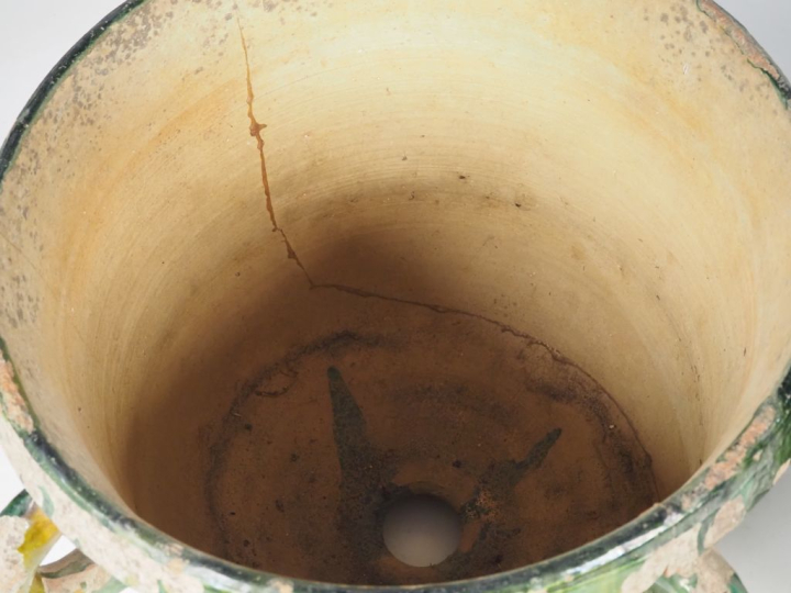 2 différents pots en terre vernissée verte nuancée de jaune, sur piédo