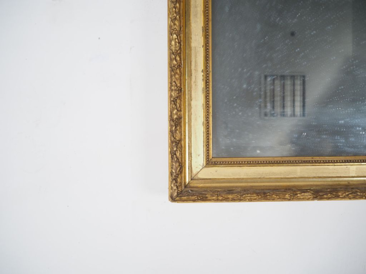 Miroir en bois et stuc doré, à décor de laurier, de fleurs et de frise