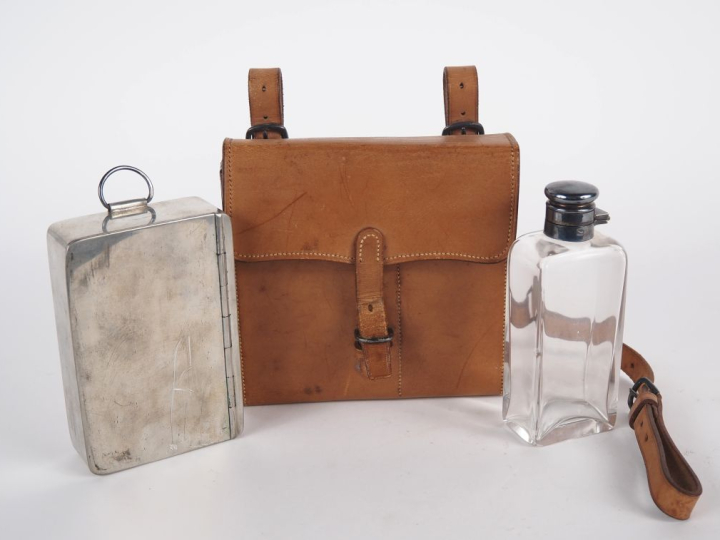 Sacoche en cuir brun contenant une boîte en métal argenté et un flacon